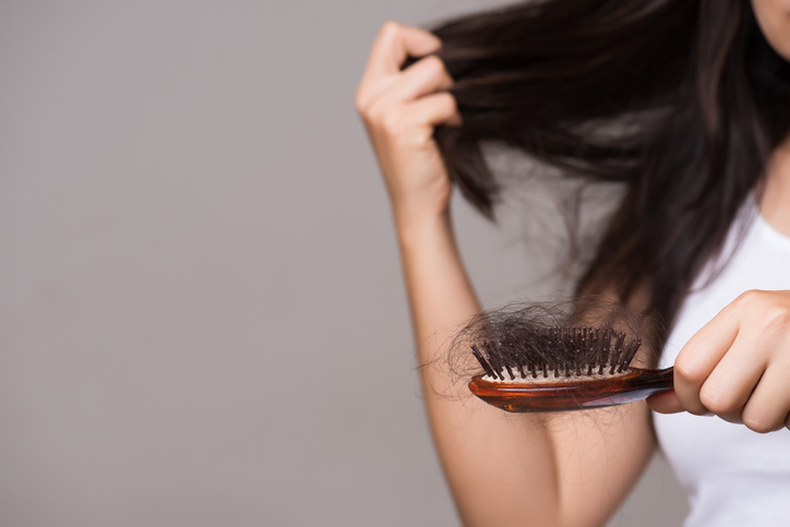 Thinning hair concept, woman showing brush holding hair that has fallen out